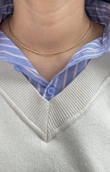 Necklace worn by a person with a blue and white striped shirt and gray sweater.