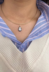 Necklace with a teardrop pendant worn by a person in a blue and white striped shirt.