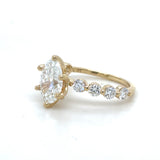 Gold ring with a large oval diamond and smaller round diamonds on a white background