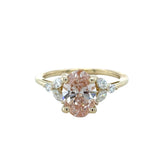 Gold ring with a pink diamond and smaller clear diamonds on a white background