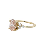Gold ring with a pink diamond and smaller diamonds on a white background