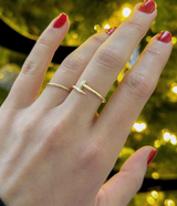 Hand wearing a gold ring with a blurred festive background
